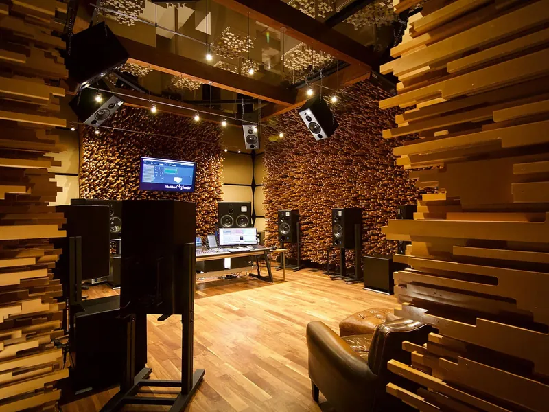 A recording studio control room with wood acoustic panels and studio monitors